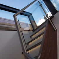 Escalera moderna con barandilla de acero inoxidable y peldaños iluminados, bajo un cielo despejado.