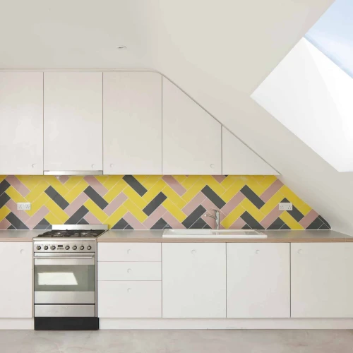 Modern kitchen featuring a sleek white cabinetry design, a stainless steel stove, and a striking yellow and geometric patterned backsplash. Natural light streams in from a skylight above.