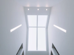 Plafond blanc avec de grandes fenêtres et des lumières intégrées. L’espace est minimaliste et épuré.