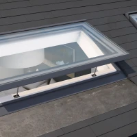 Two skylights on a sloped roof, each featuring a rectangular design with clear glass panes, allowing light to enter into a modern interior space. The roof is covered with dark shingles, and one skylight partially reveals a glimpse of a light fixture inside.